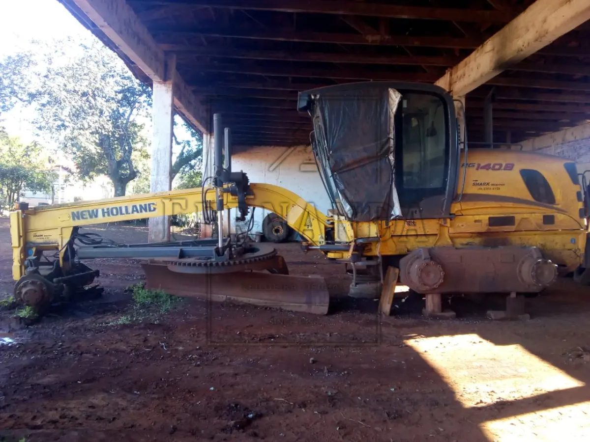 LOTE 009 - – Motoniveladora New Holland RG140B, ano 2011, com aros, sem pneus, portas comidros quebrados